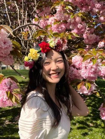 Sharon Liu in front of a cherry blossom tree. 