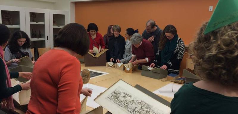 Photo of people in Special Collections Seminar room, looking at rare books.