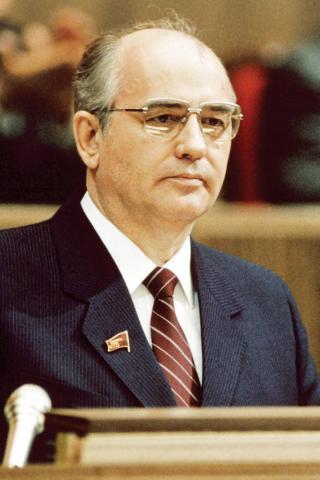 Mikhail Gorbachev seated behind microphones