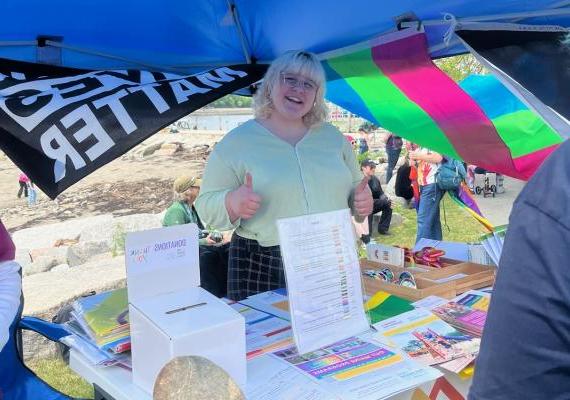 Alex Barstow smiling with thumbs up in front of a table under a tent