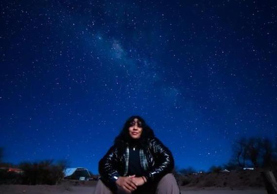 贾兹敏坐在满天的繁星下. 