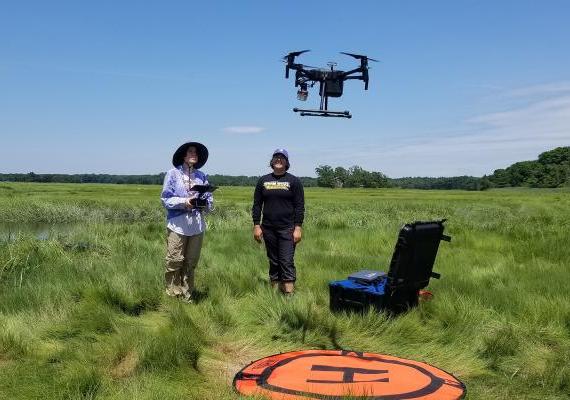 乔斯林·布拉沃和安吉拉·考林在梅岛的沼泽地里操作一架无人机.