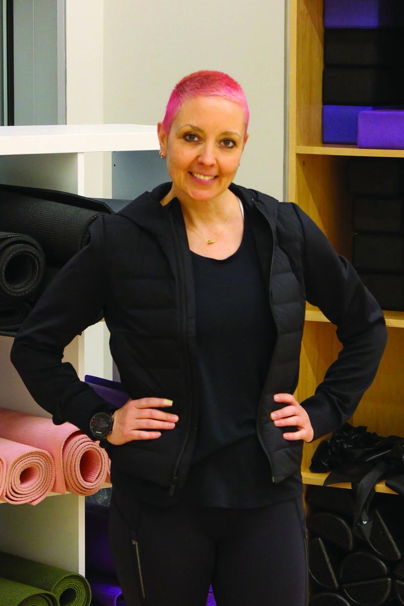 Portrait of Courtney Morris in front of a shelf full of yoga mats