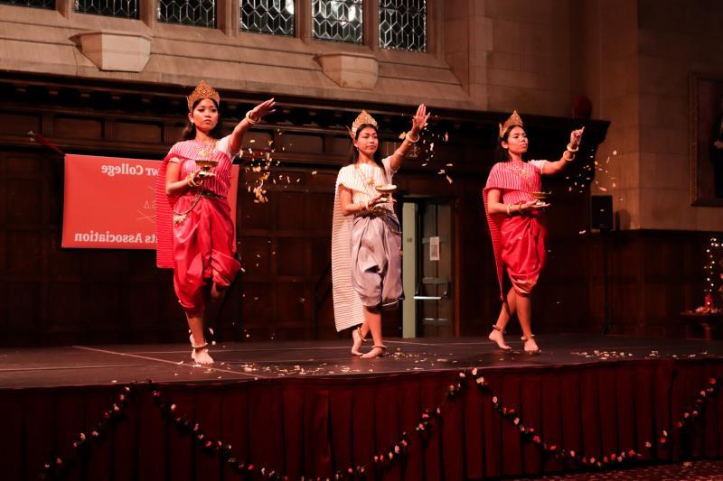 三名身穿柬埔寨传统服装的妇女站在舞台上撒花瓣. 