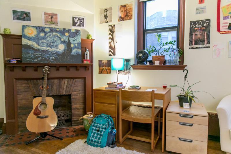Dorm room with fireplace, desk, and guitar